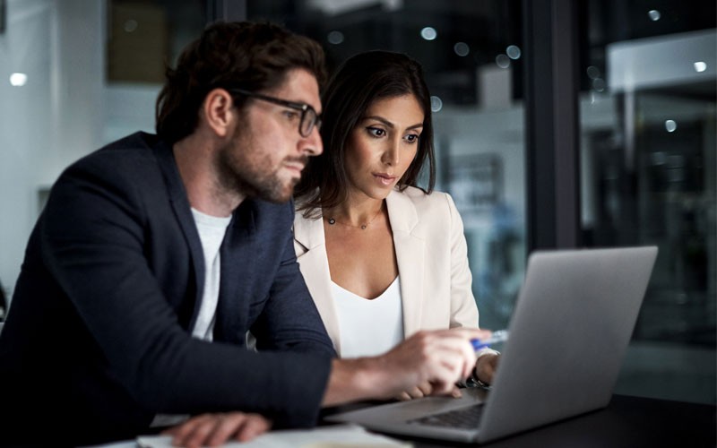 Two coworkers looking at laptop device