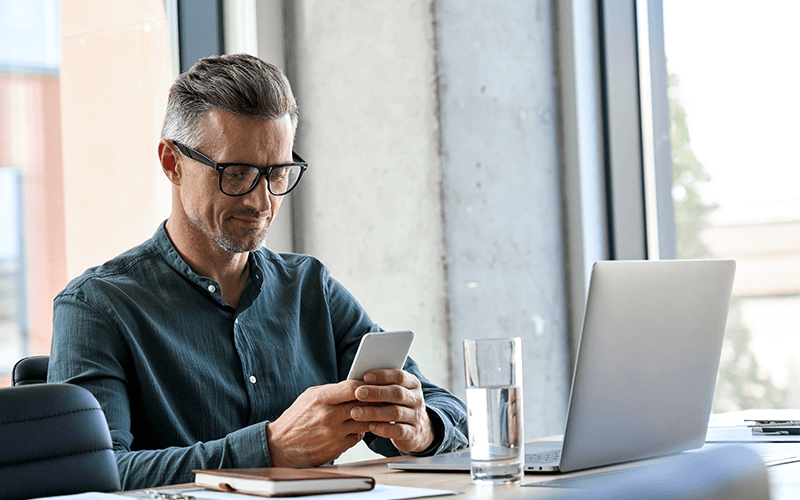 Man with glasses on phone and computer