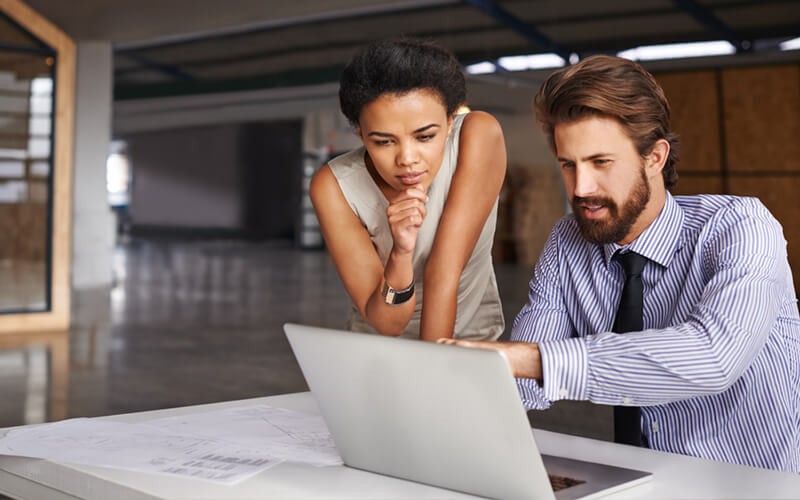 Two business professionals use deployment services on laptop computer