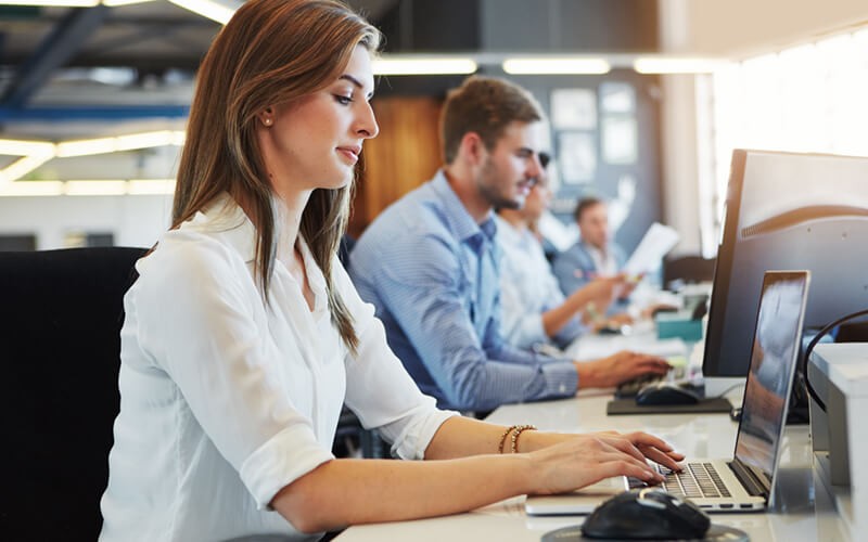 Businesswoman working efficiently at laptop computer in open office